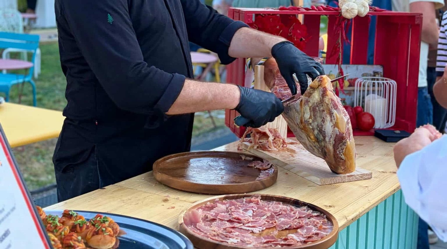 Découpe d'un jambon à la main sur un stand de showcooking lors d'un événement d'entreprise.