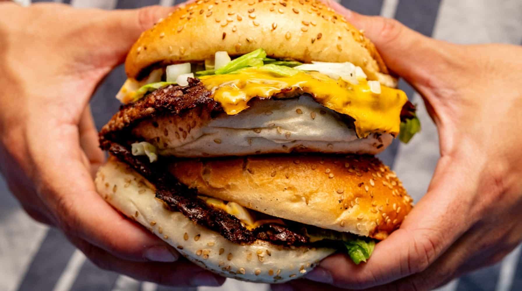 Burger street food gastronomique tenu à deux mains lors d'un événement.