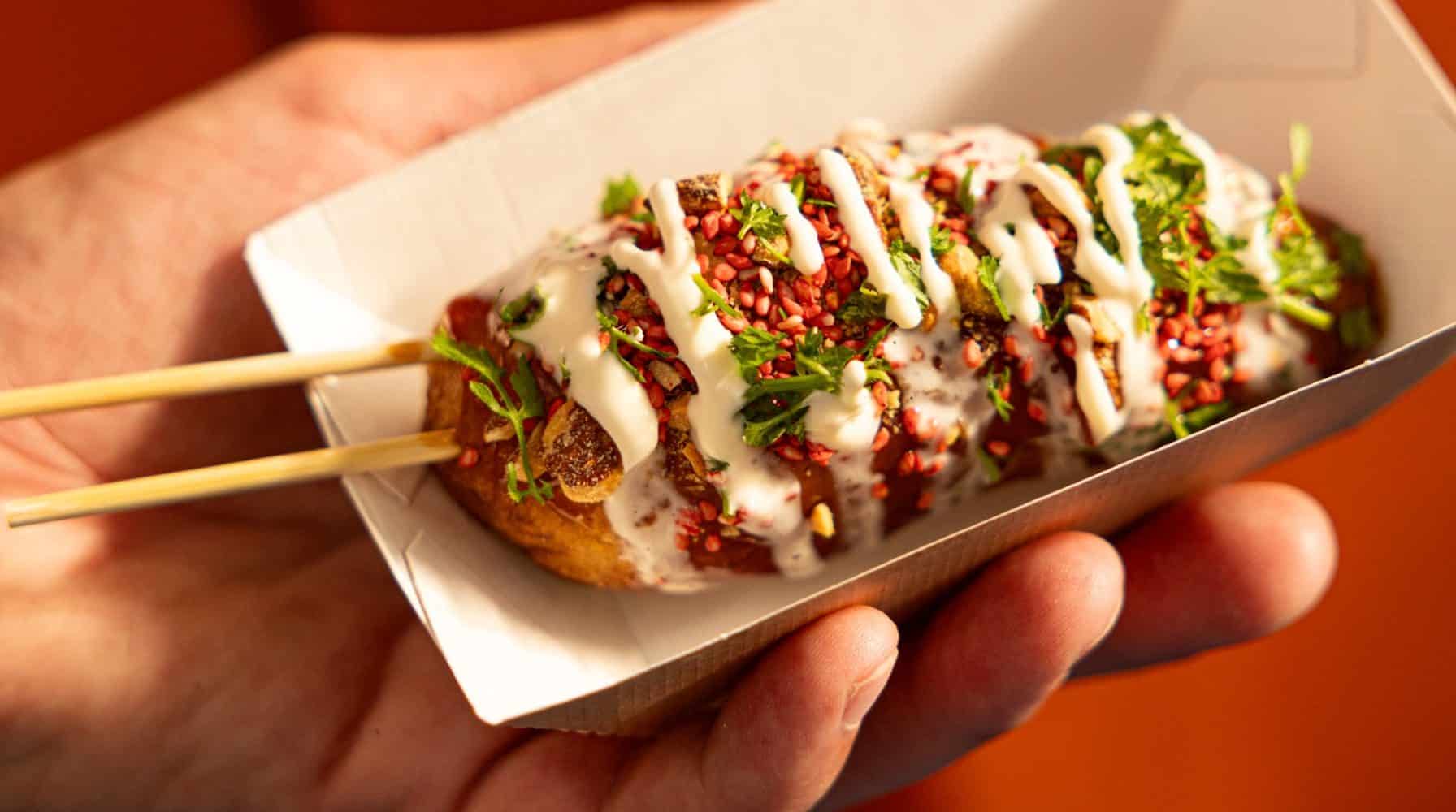 Hot-dog gastronomique dressé dans une barquette, servi en street food événementielle.