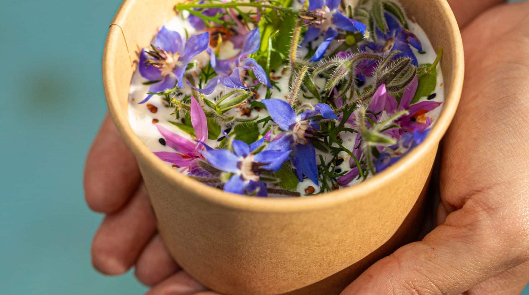 Bol en carton kraft garni de fleurs comestibles, servi par un traiteur éco responsable.