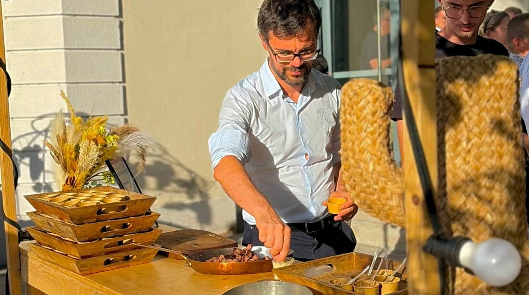 Un chef dresse des bouchées sur un buffet en bois lors d'un événement d'entreprise.