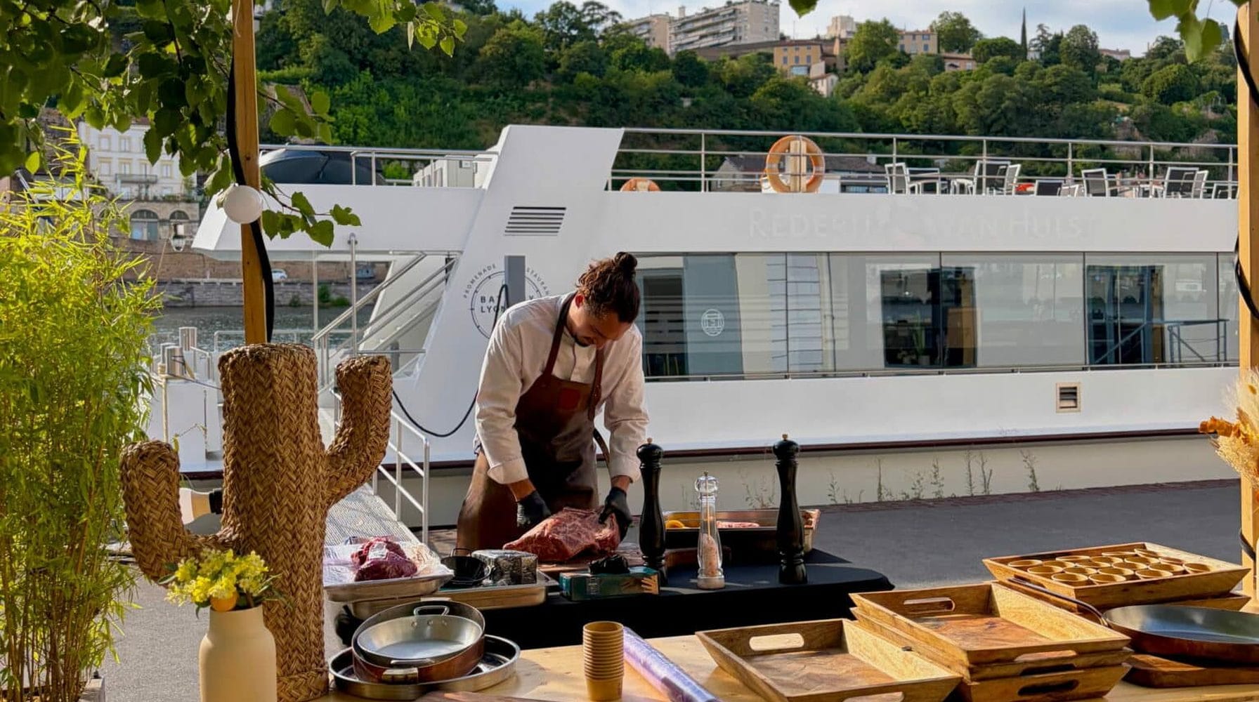 Chef en cuisine nomade au bord de l'eau, plancha et décor sur mesure pour un événement.